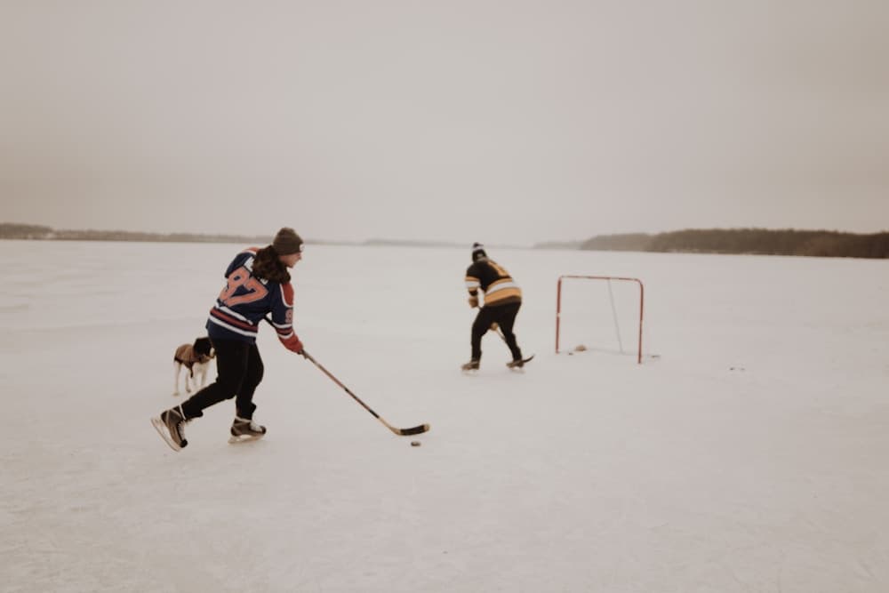 Friends and a dog playing pond hockey in old jerseys